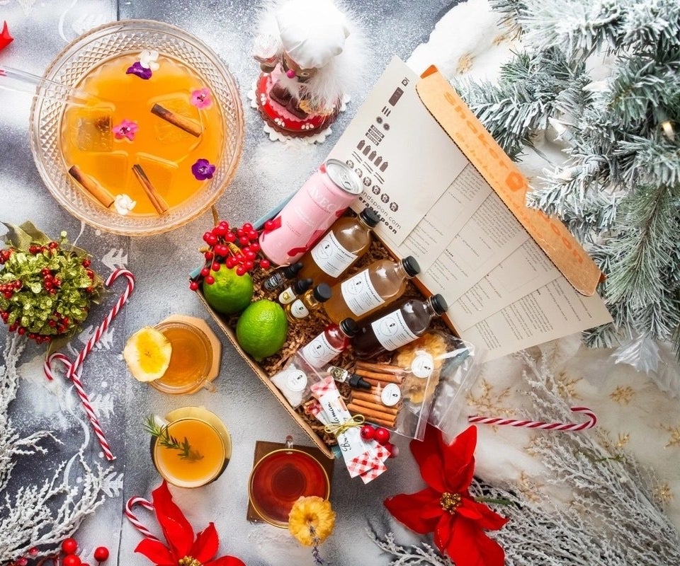 The cocktail club subscription box featuring cocktail ingredients surrounded by festive holiday decor and a punch bowl