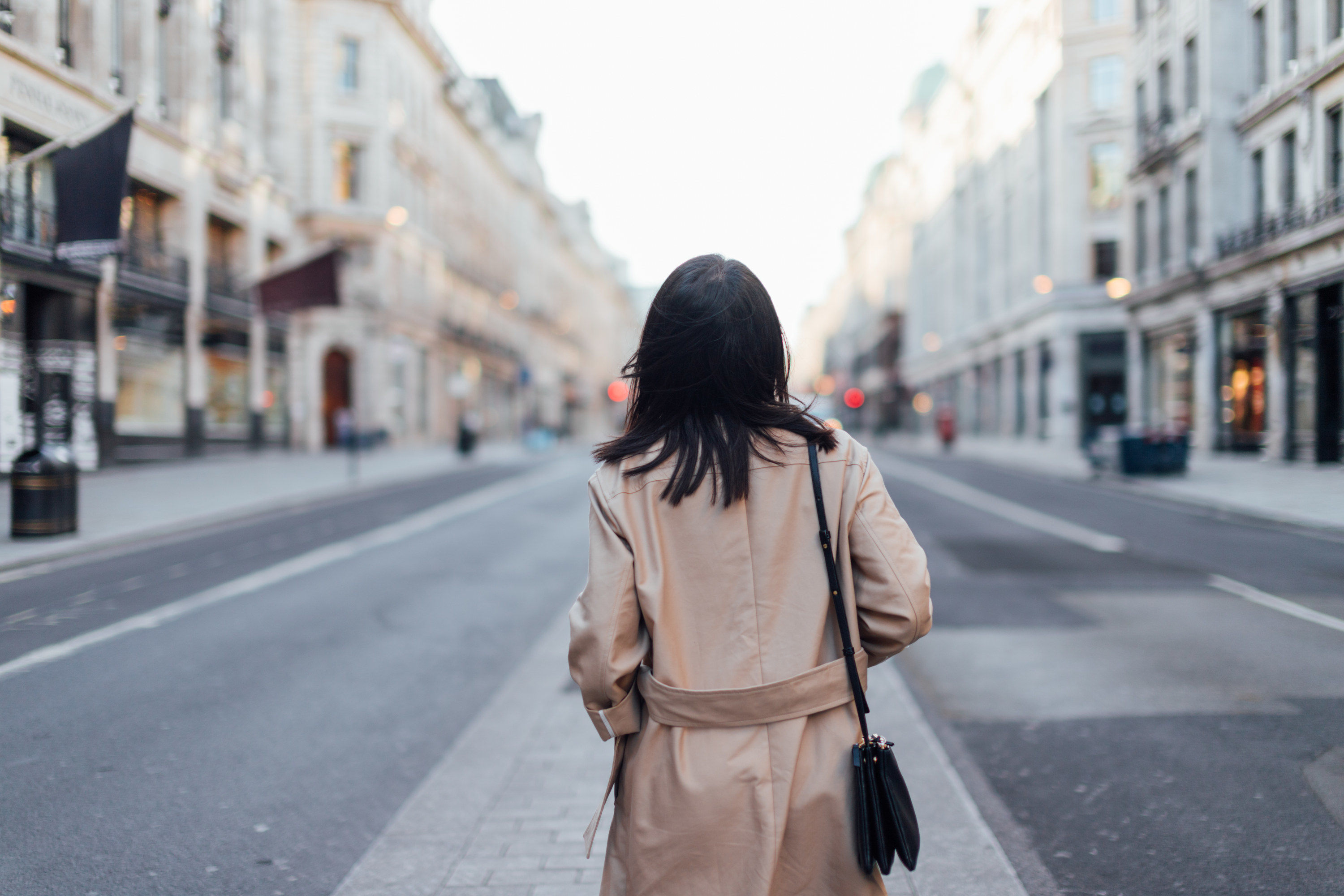 Rear view of a young woman walking on the shopping street in the city.