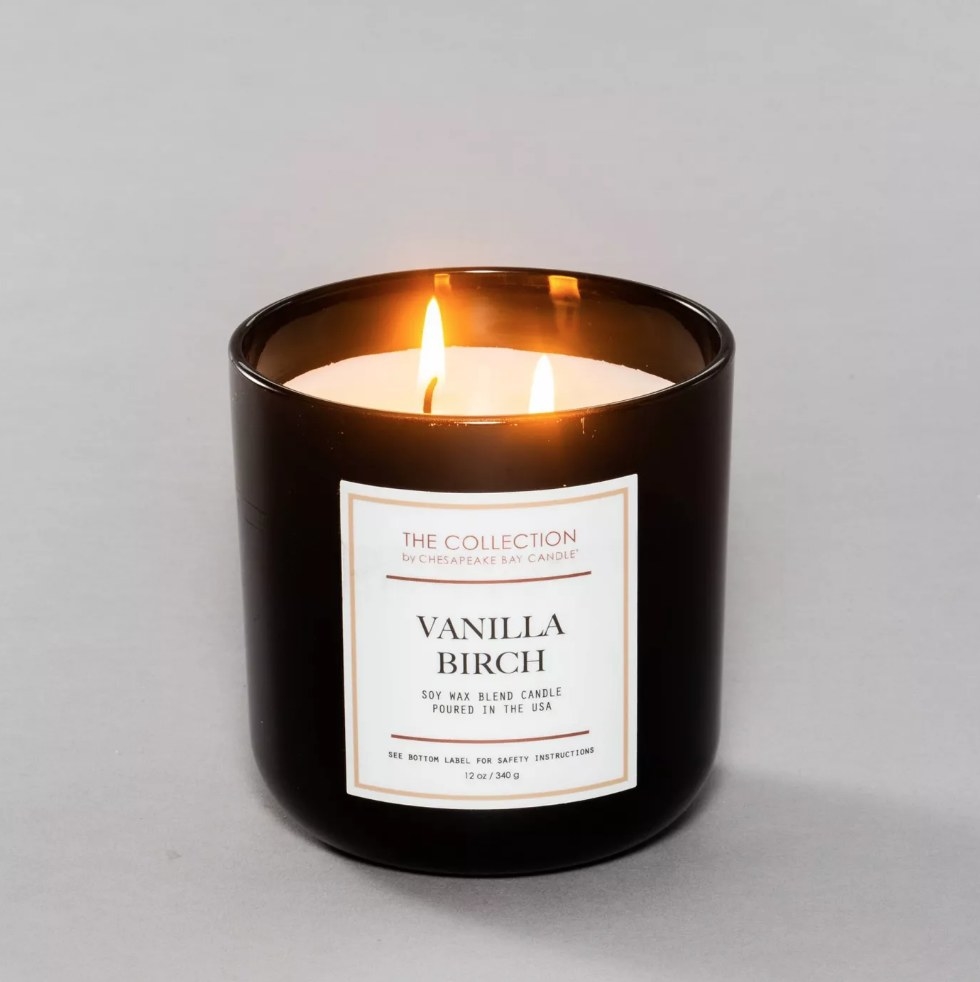 White two wick candle burning in black jar with white label