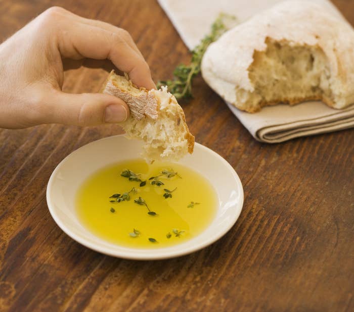 Dipping crusty bread into olive oil.