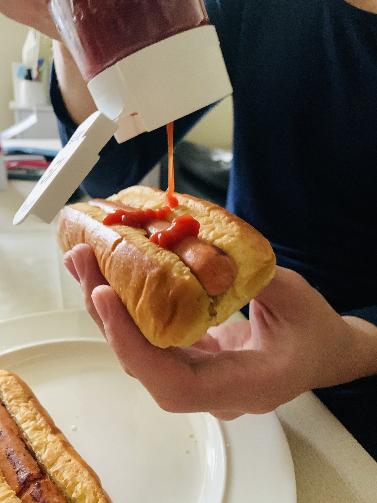 Squeezing ketchup on hotdog.