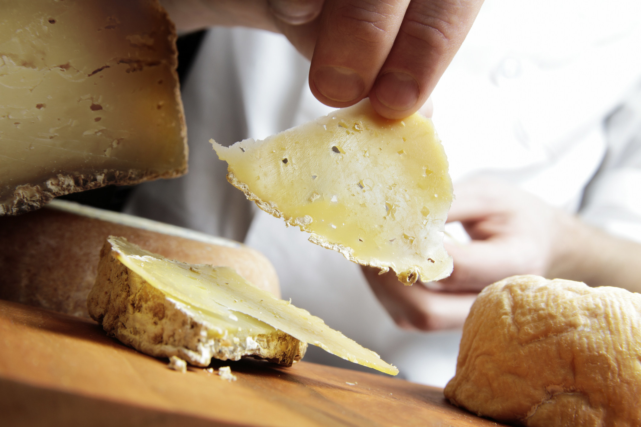 Hands removing fresh sliced hard Italian pecorino Romano cheese.