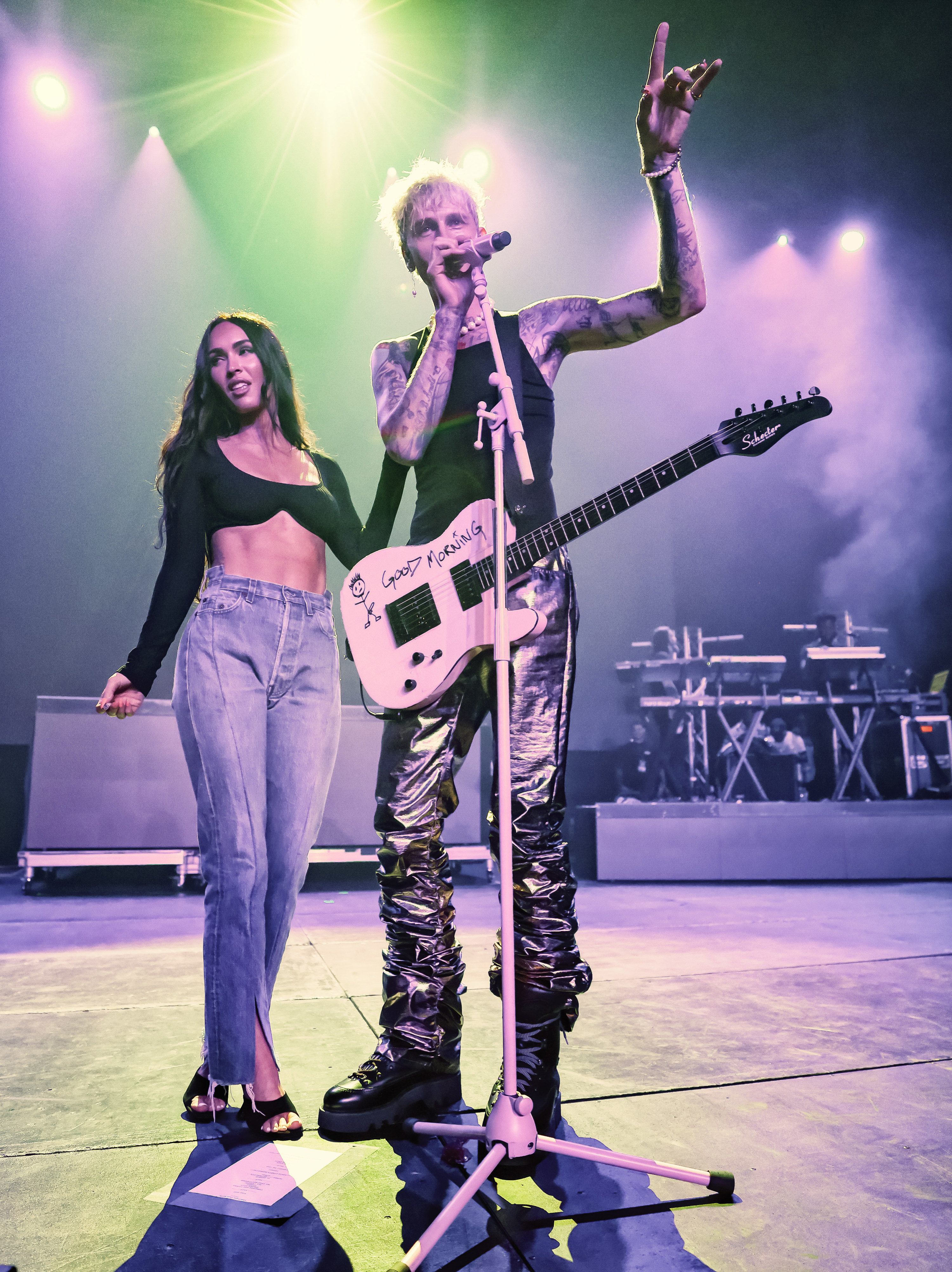 Machine Gun Kelly sings into the microphone next to Megan Fox