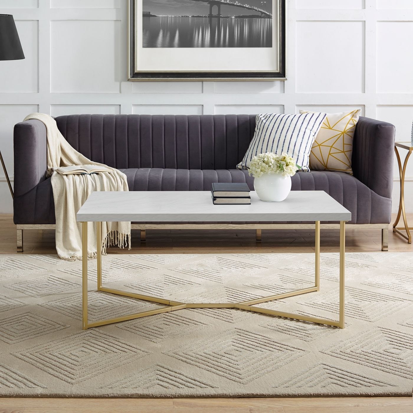 The rectangular gold and faux marble table in front of a purple couch