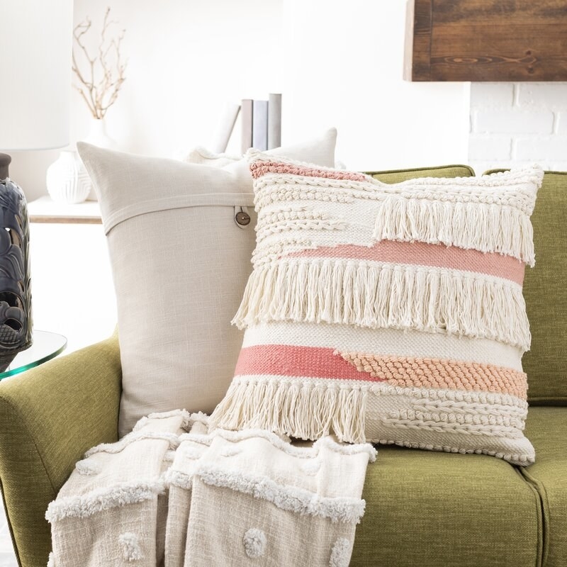 Throw pillow on a sofa with a blanket and another pillow