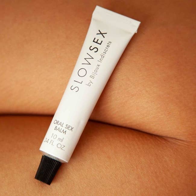 White tube of Slow Sex oral sex balm on model's body