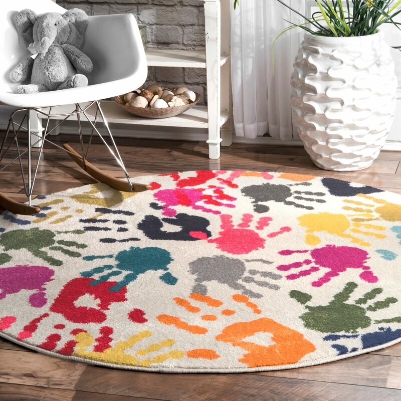 The round area rug with handprints in a living room