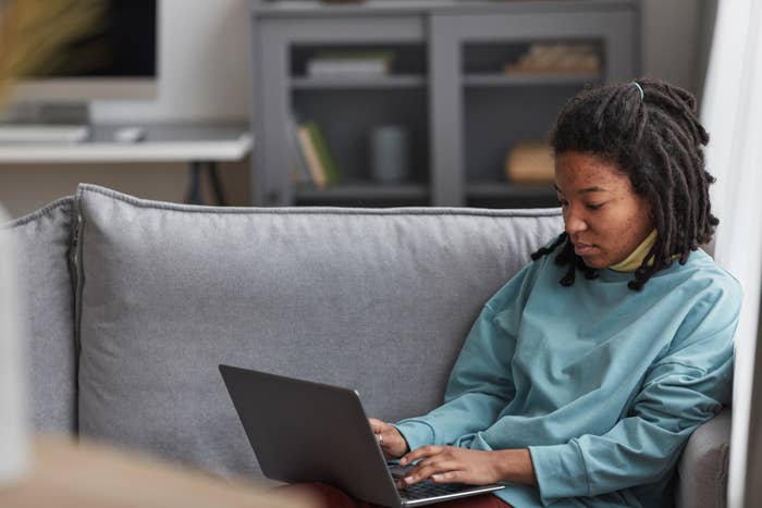 A woman wearing no makeup working on a laptop