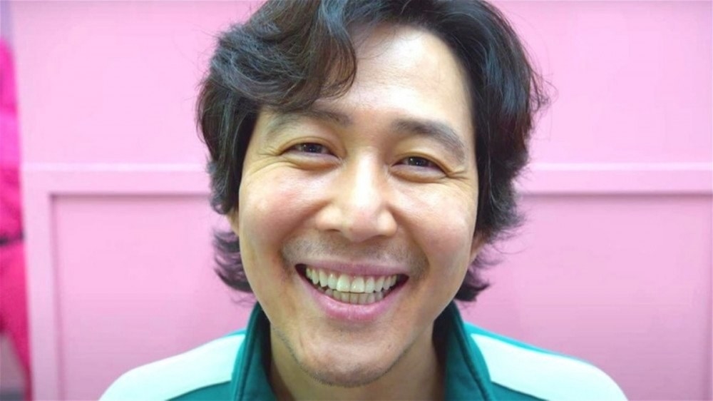 Actor Lee Jung-jae, dressed in a green shirt and smiling widely for his role as Seong Gi-hun in the Netflix show Squid Game
