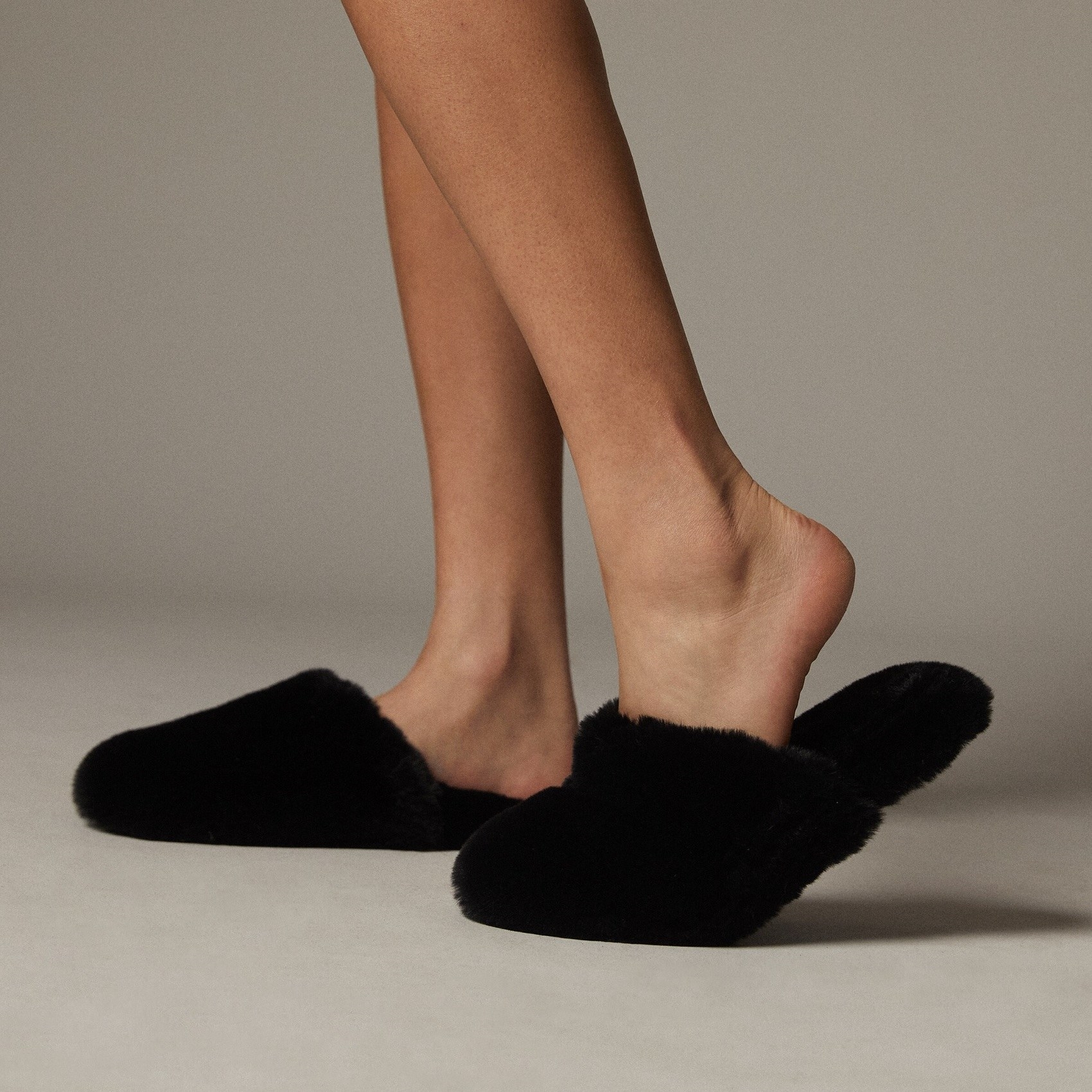 A person wearing furry slippers on their feet