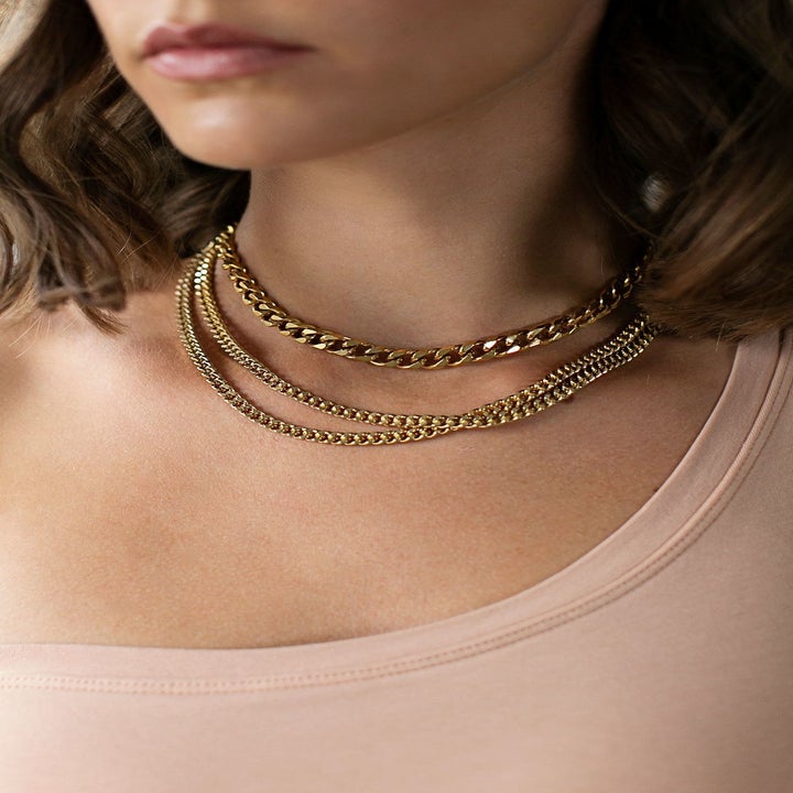 several gold chokers around a model's neck