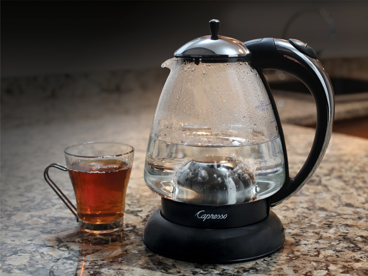 Water kettle next to a glass cup of tea