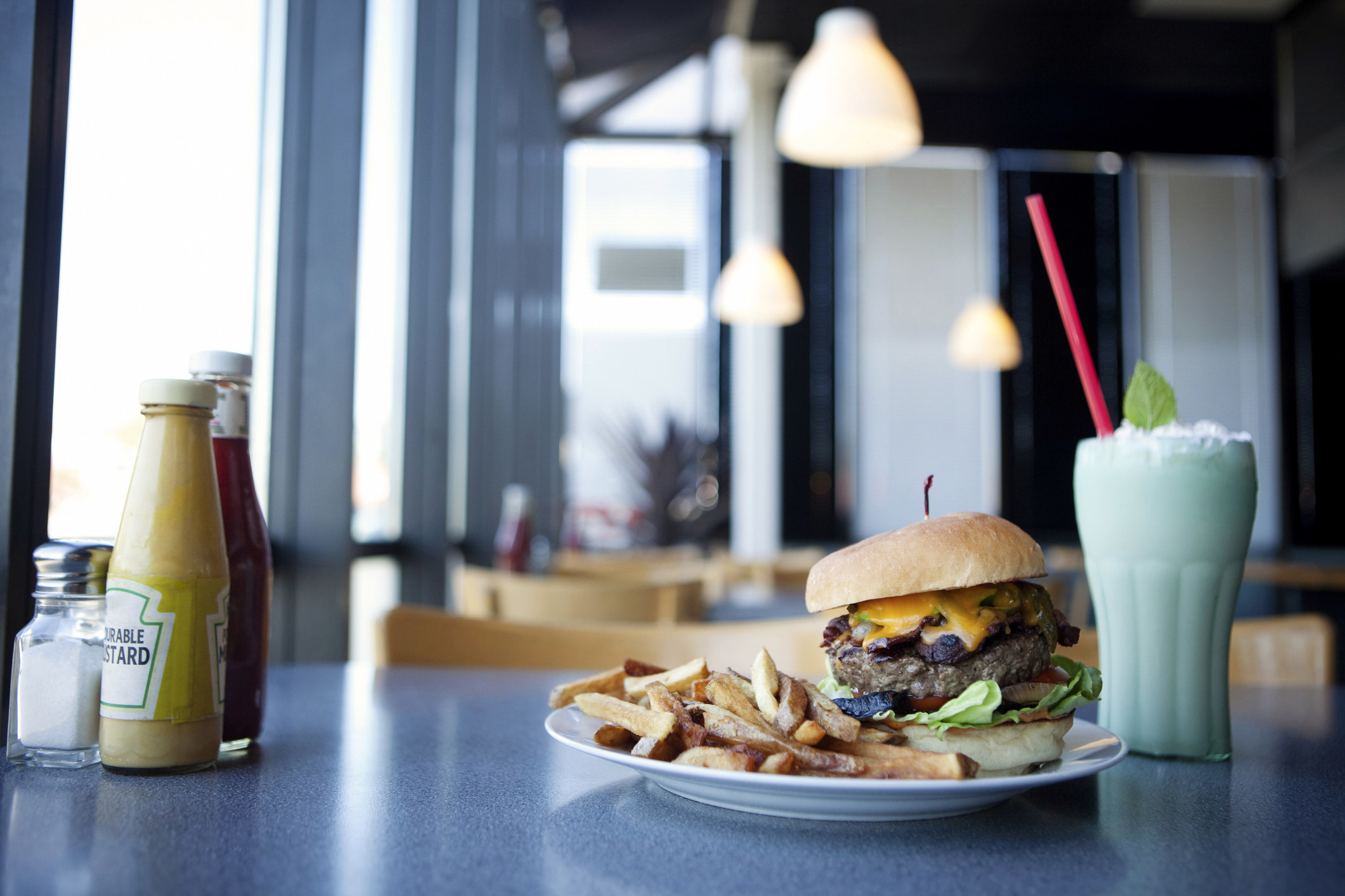 A burger, fries, and a green milkshake.