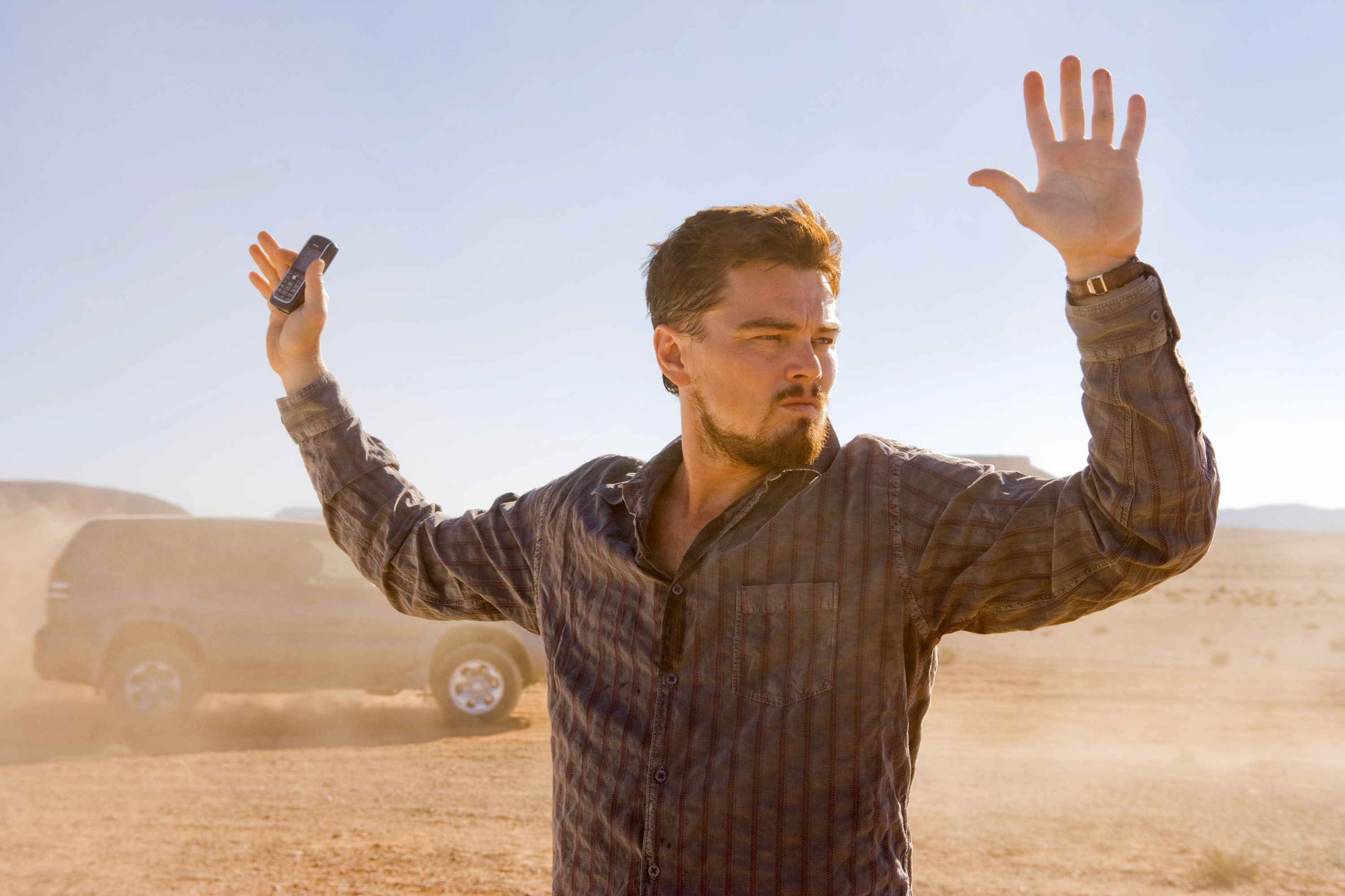 Leonardo DiCaprio puts his hands up in the desert