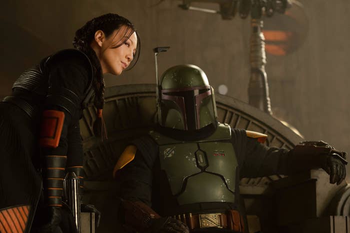 Boba Fett on the throne with Fennec Shand whispering to him