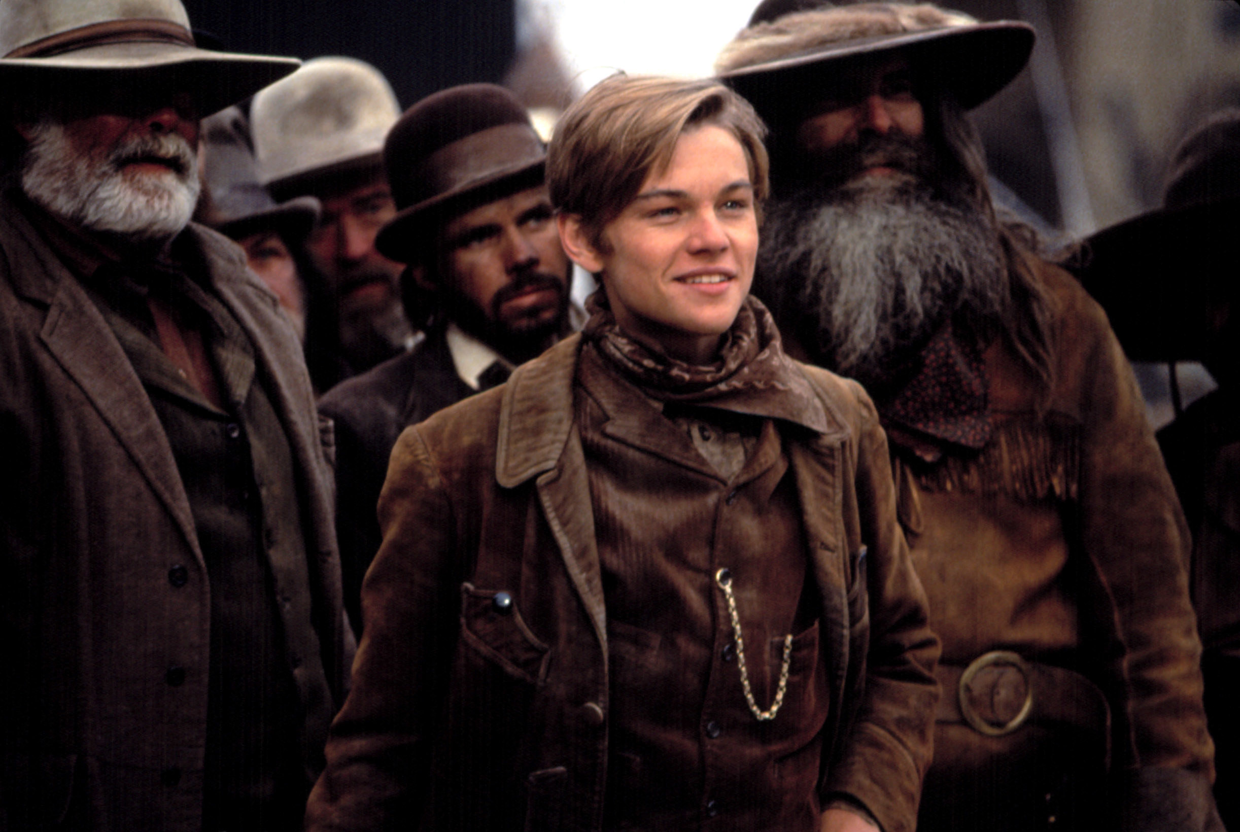 Leonardo DiCaprio stands with a bunch of cowboys