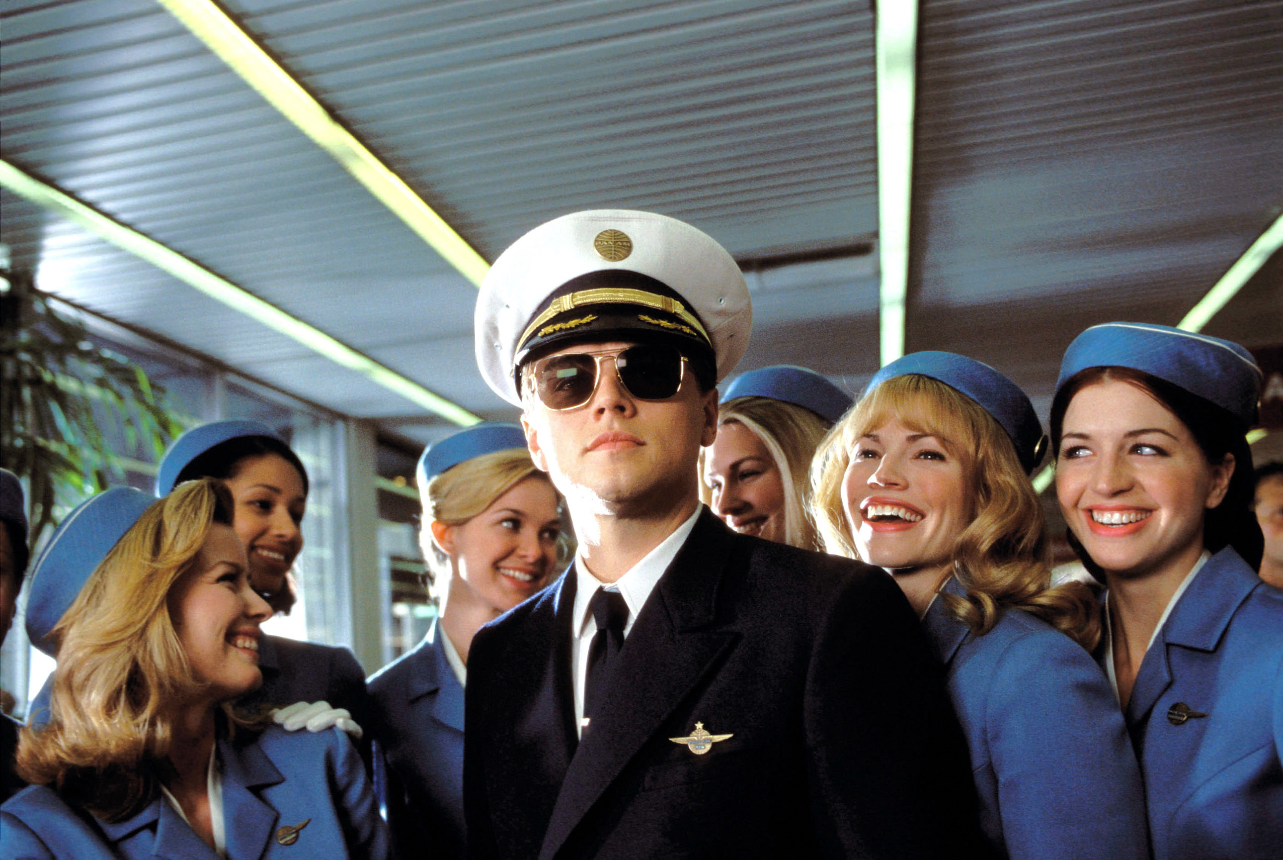 Leonardo DiCaprio dressed as a pilot surrounded by flight attendants