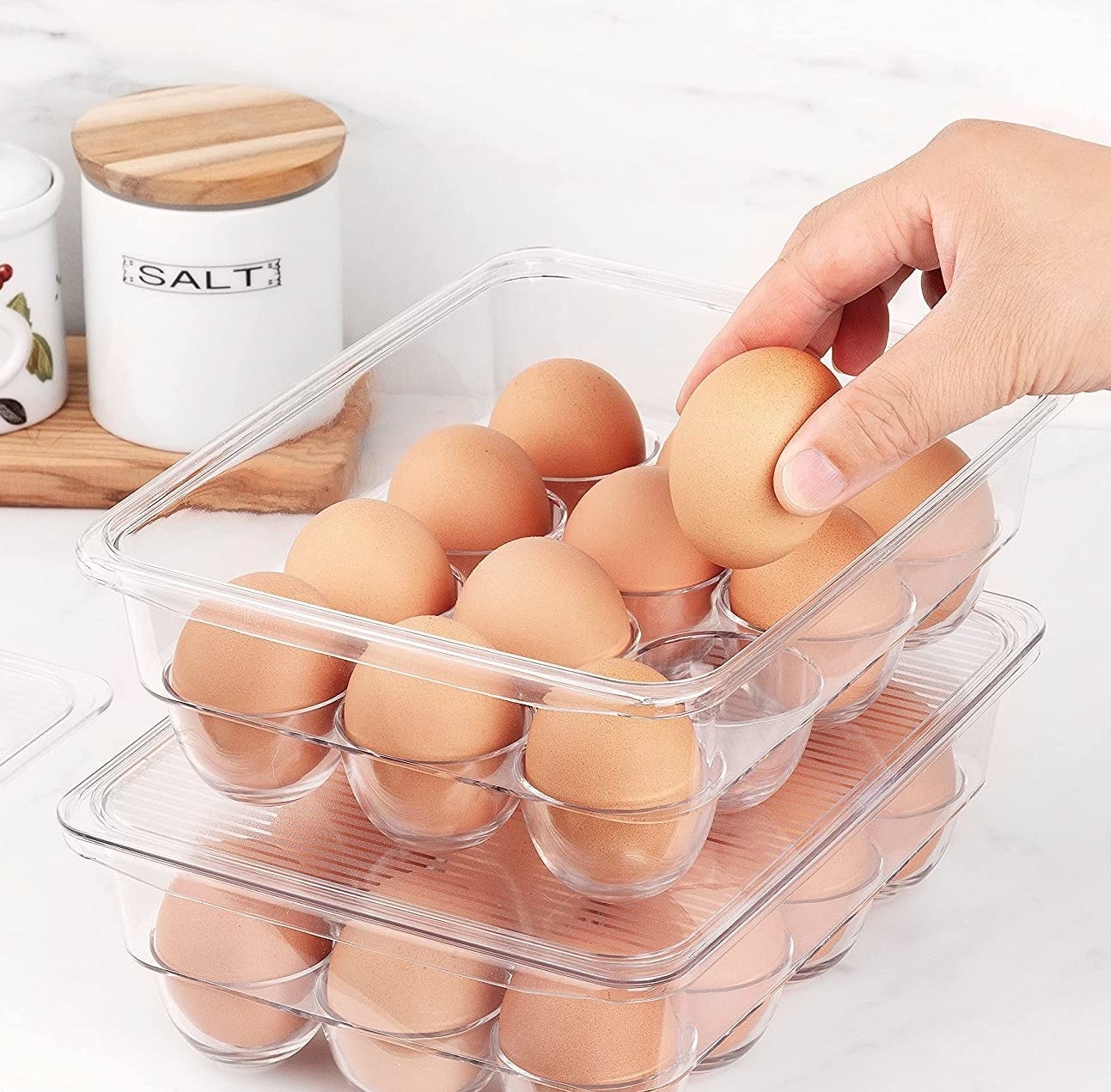 A person putting an egg into an almost-full egg container