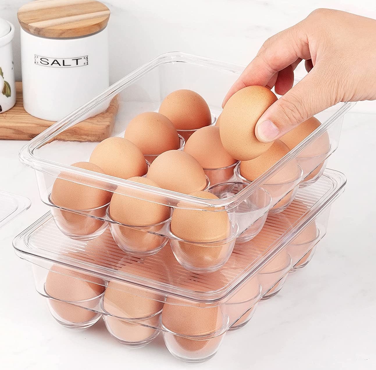 A person putting an egg into an almost-full egg container