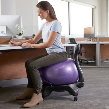 Model sitting on purple exercise ball chair in an office