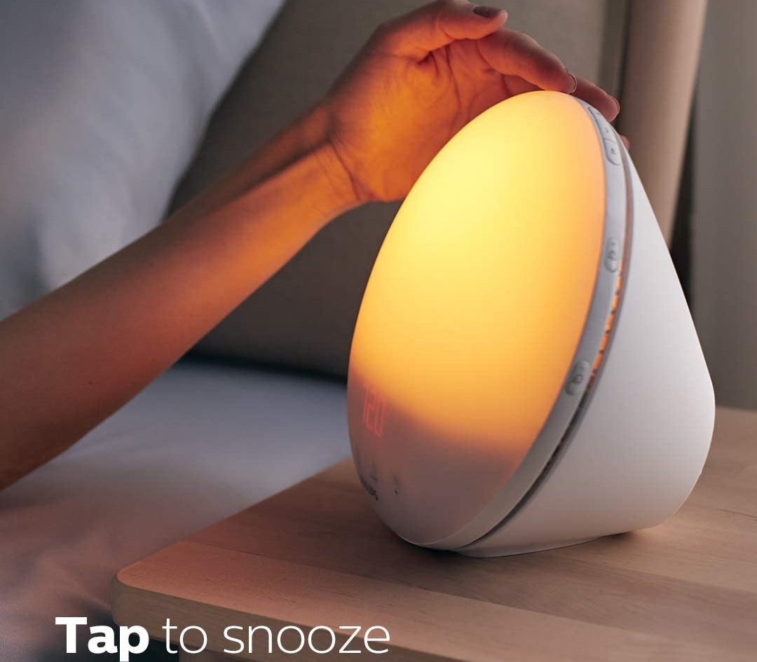a person touching the top of the sunrise alarm clock