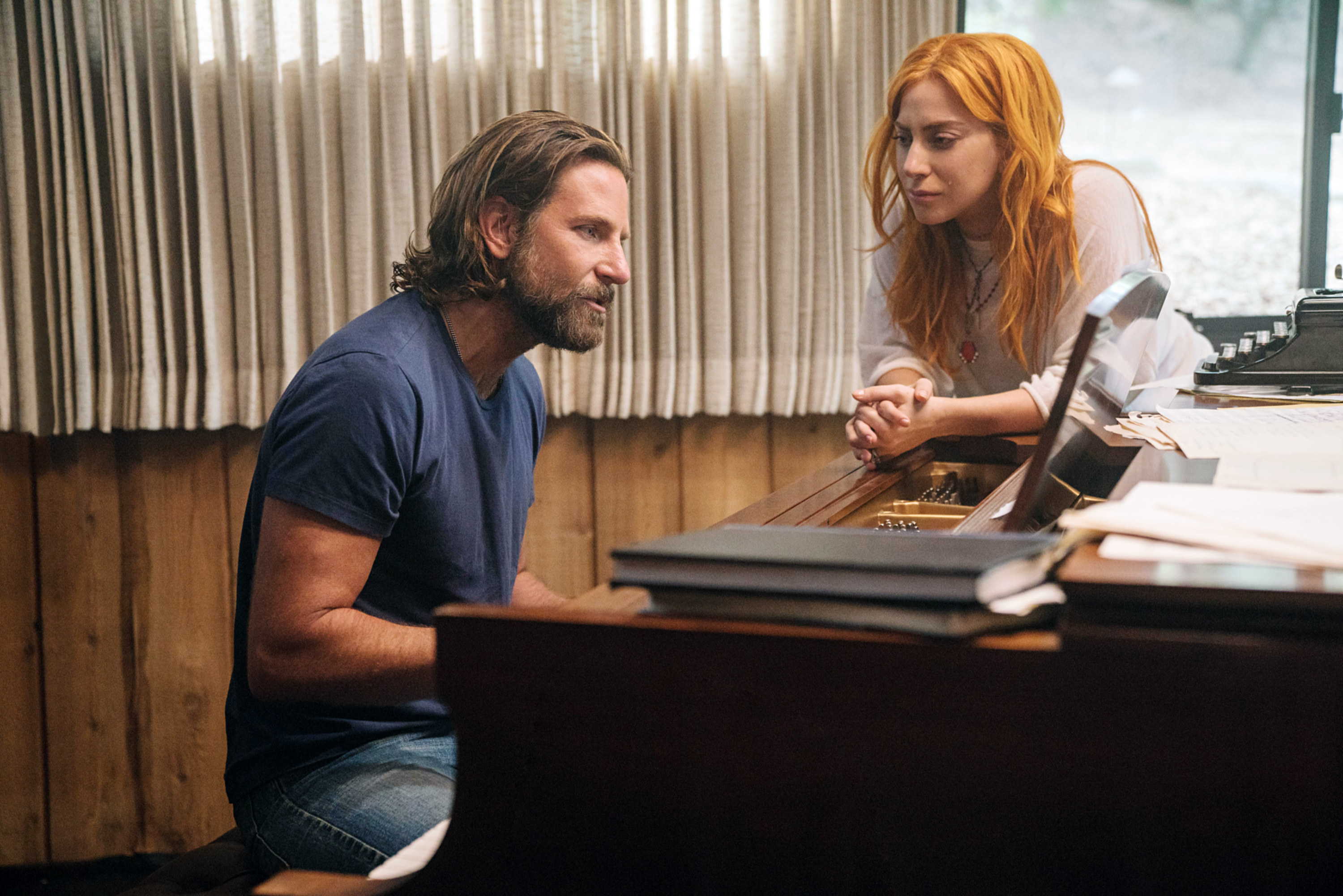 Ally standing by a piano in a scene from A Star is Born