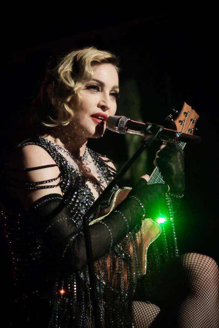 Madonna singing and playing a ukelele onstage