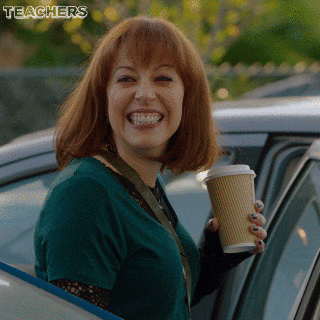 A teacher aggressively smiling with a cup of coffee