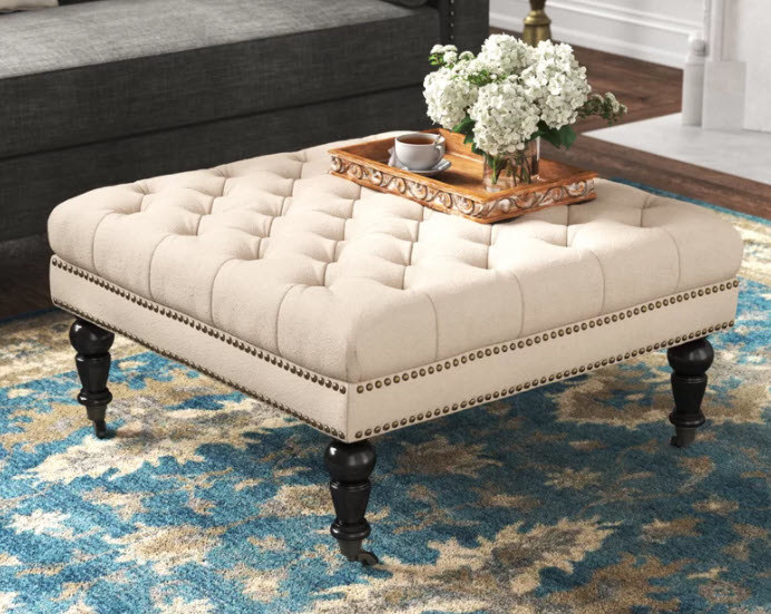 A large tufted square ottoman in cream