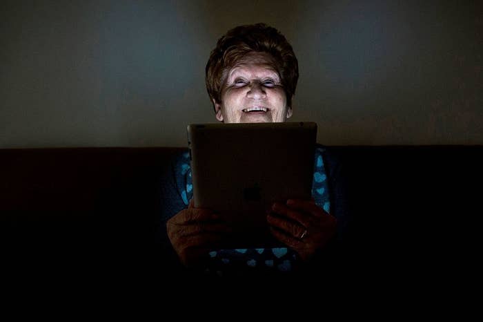 an older woman on an ipad in a dark room
