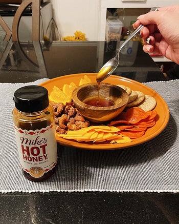 reviewer drizzles Mike's Hot Honey onto nuts and cured meats