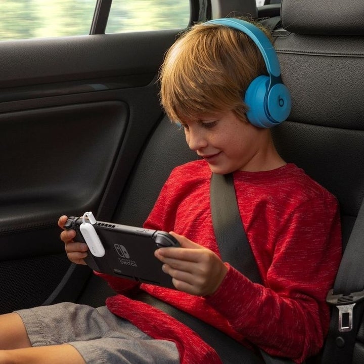 a child playing on their tablet with the dongle paired with their wireless headphones