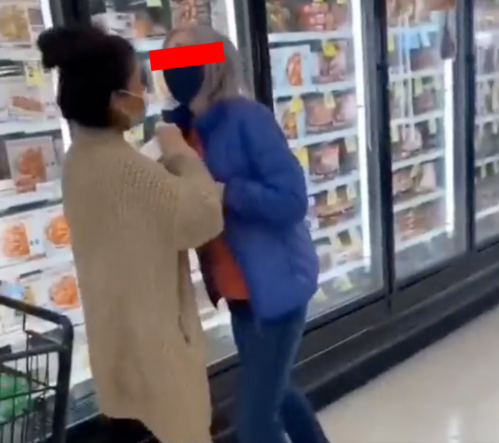 a woman pushes another woman and steals her shopping cart