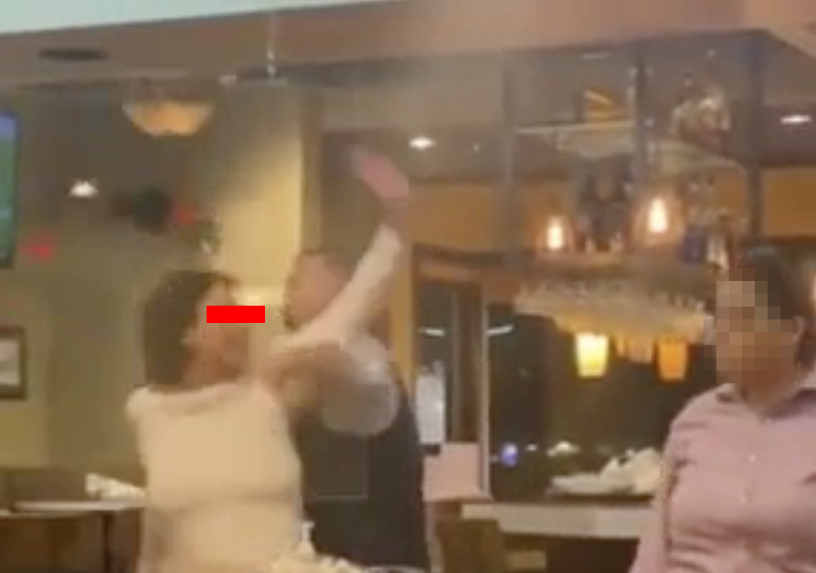 woman reaching to hit a worker but being held back
