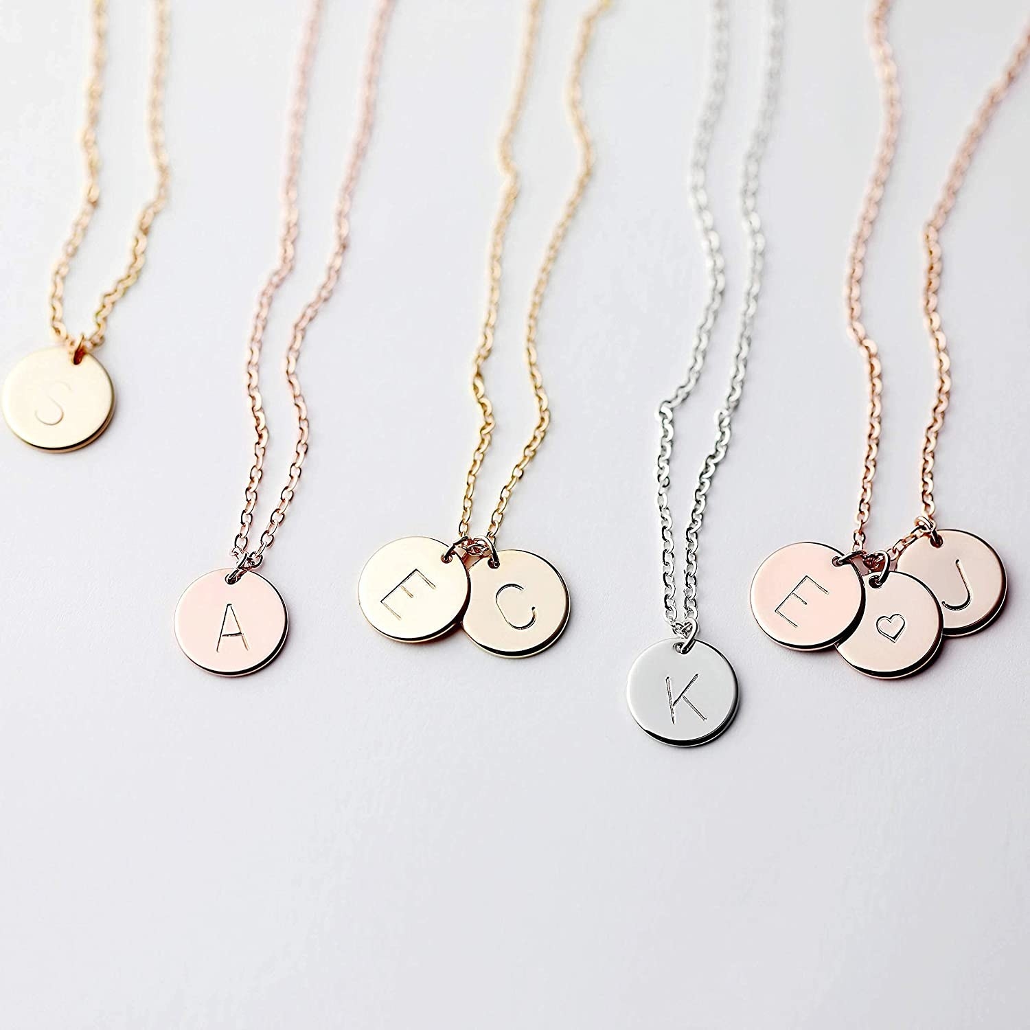 an array of delicate necklaces with intial disc charms