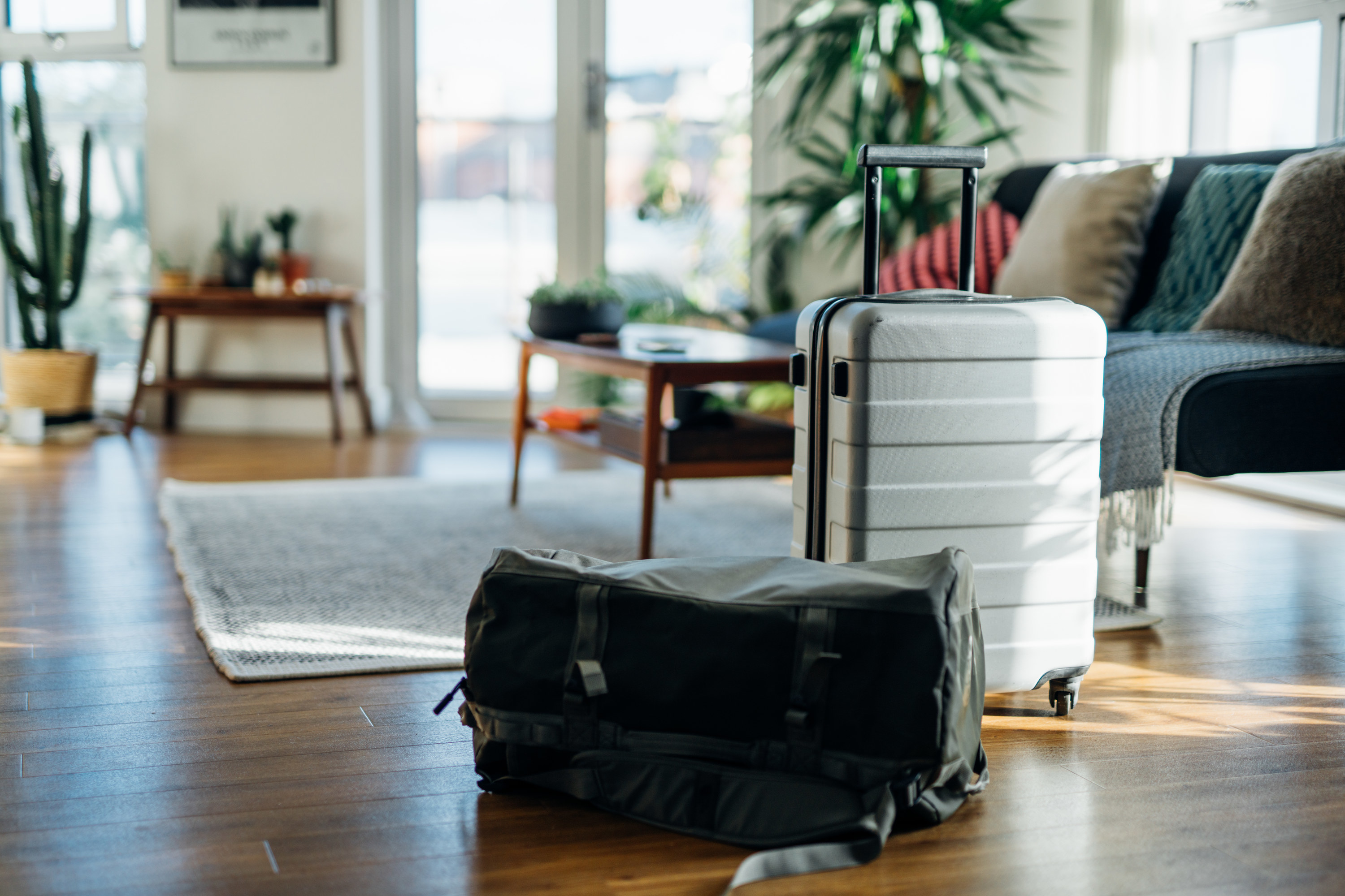 An apartment with  white suitcase and a black duffle bag on the floor