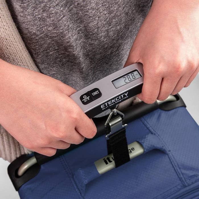 A person holding a suitcase with the luggage scale
