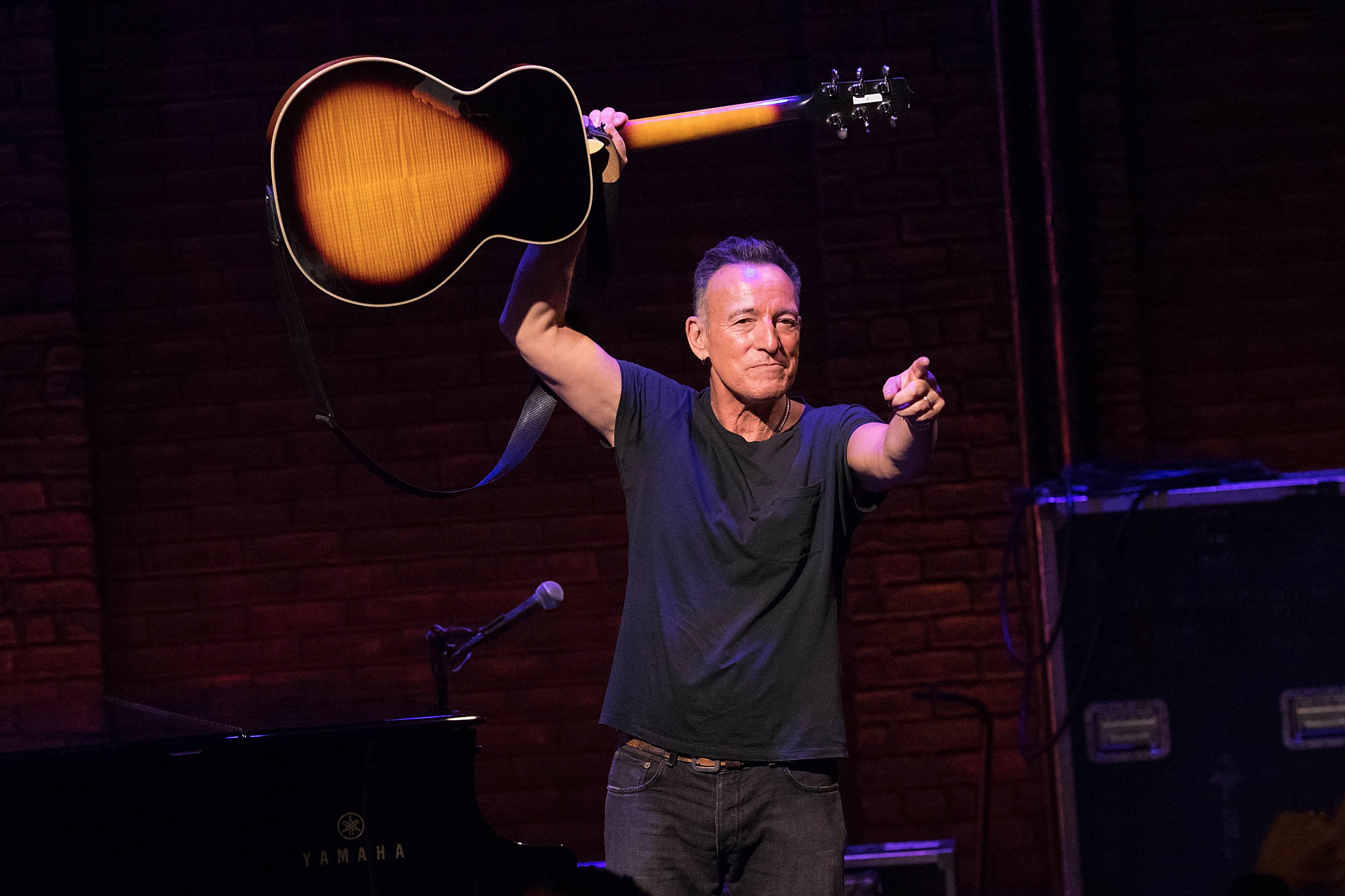 Bruce pointing and holding up a guitar