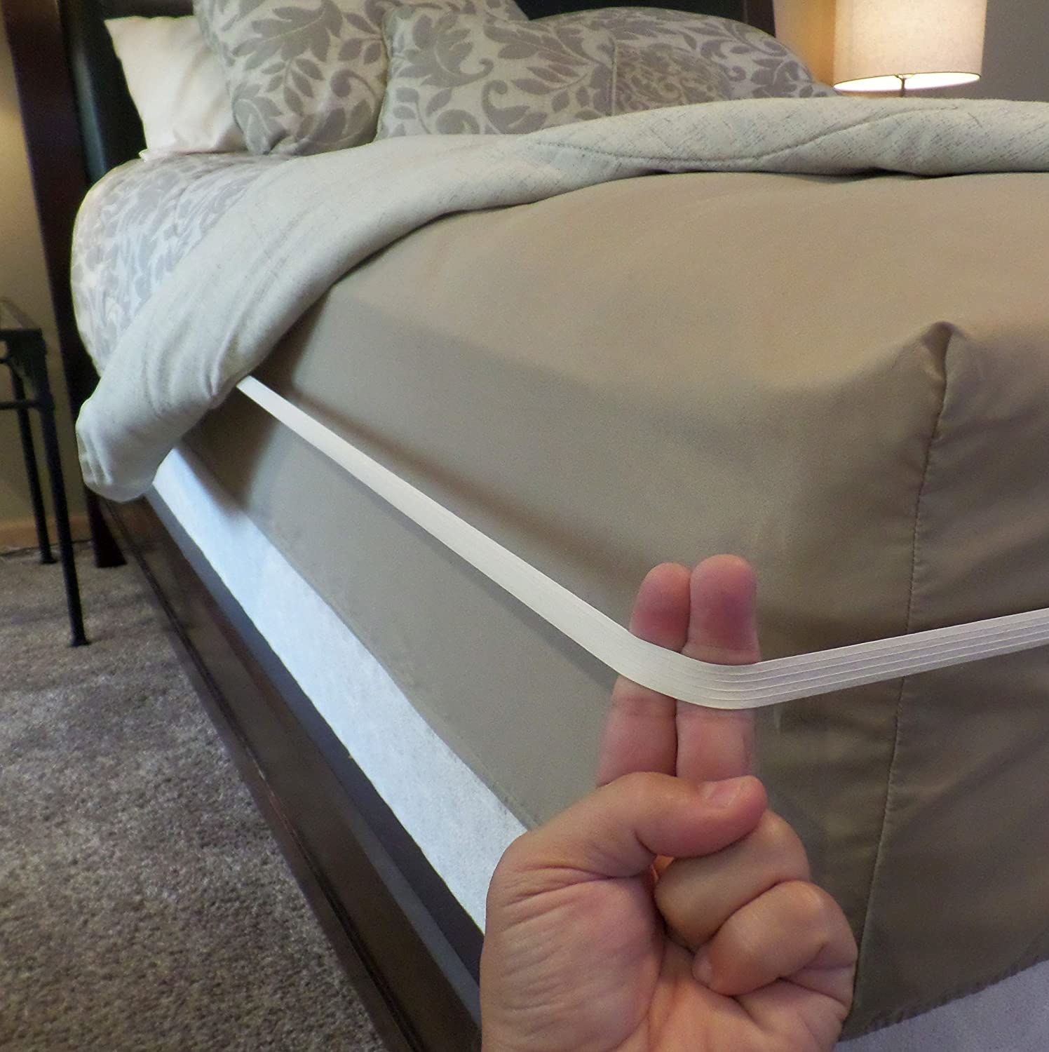 hand holding the white band, which wraps around the entire side of a mattress