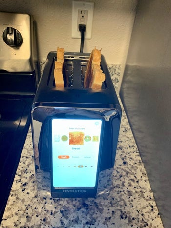 top front view of the same toaster's high-tech screen showing toasting level of bread and two toasted pieces of bread inside the slots