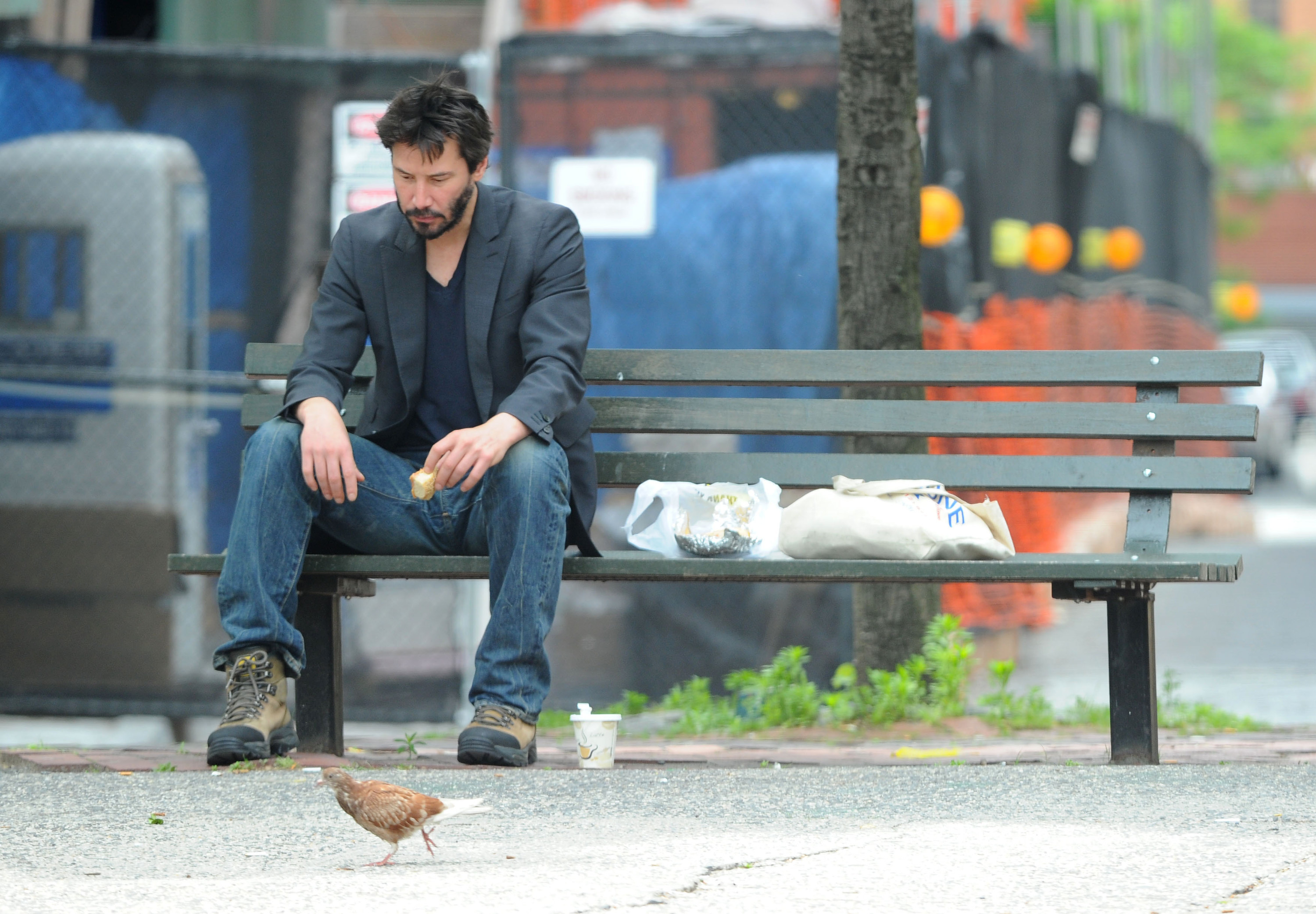 Keanu sits on a park bench and eats lunch