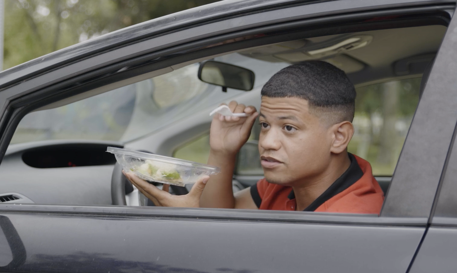 gadiel in a car&#x27;s driver&#x27;s seat holding a salad