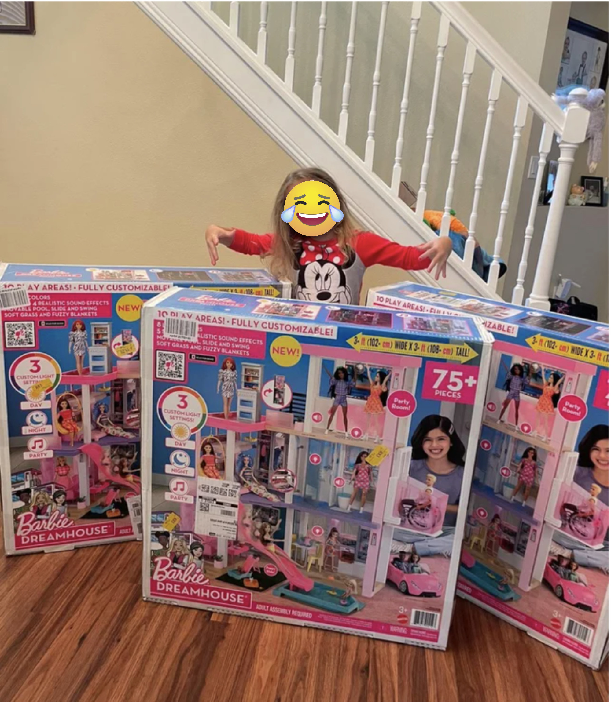 A girl stands in front of three large barbie boxes