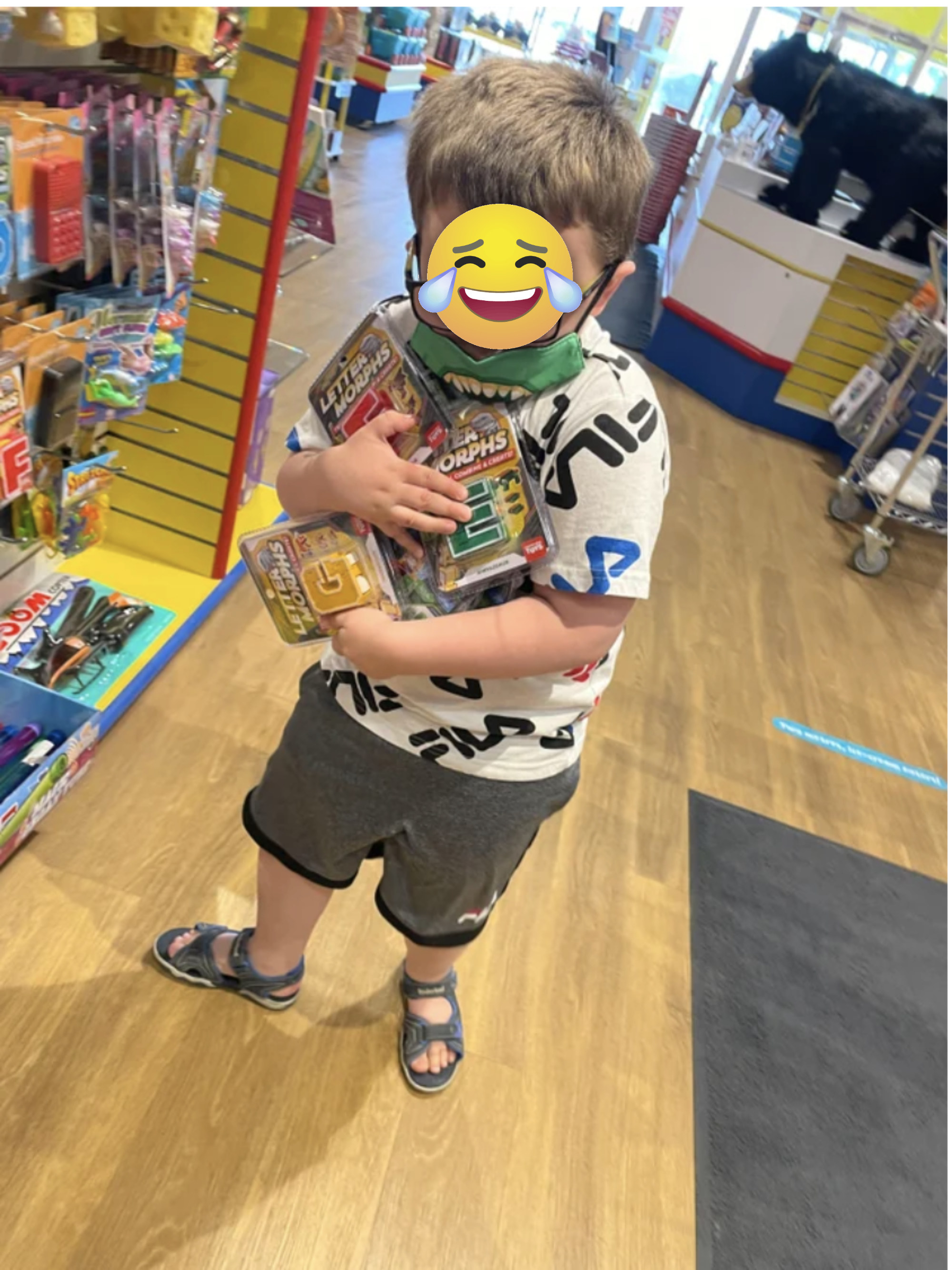 A kid holds a lot of toys in a toy store