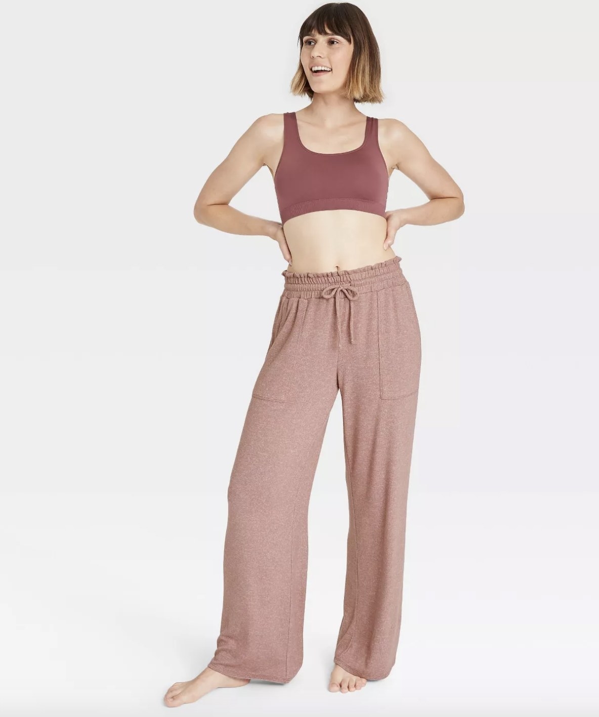 An adult is wearing a pair of mauve loose-fitting sweatpants