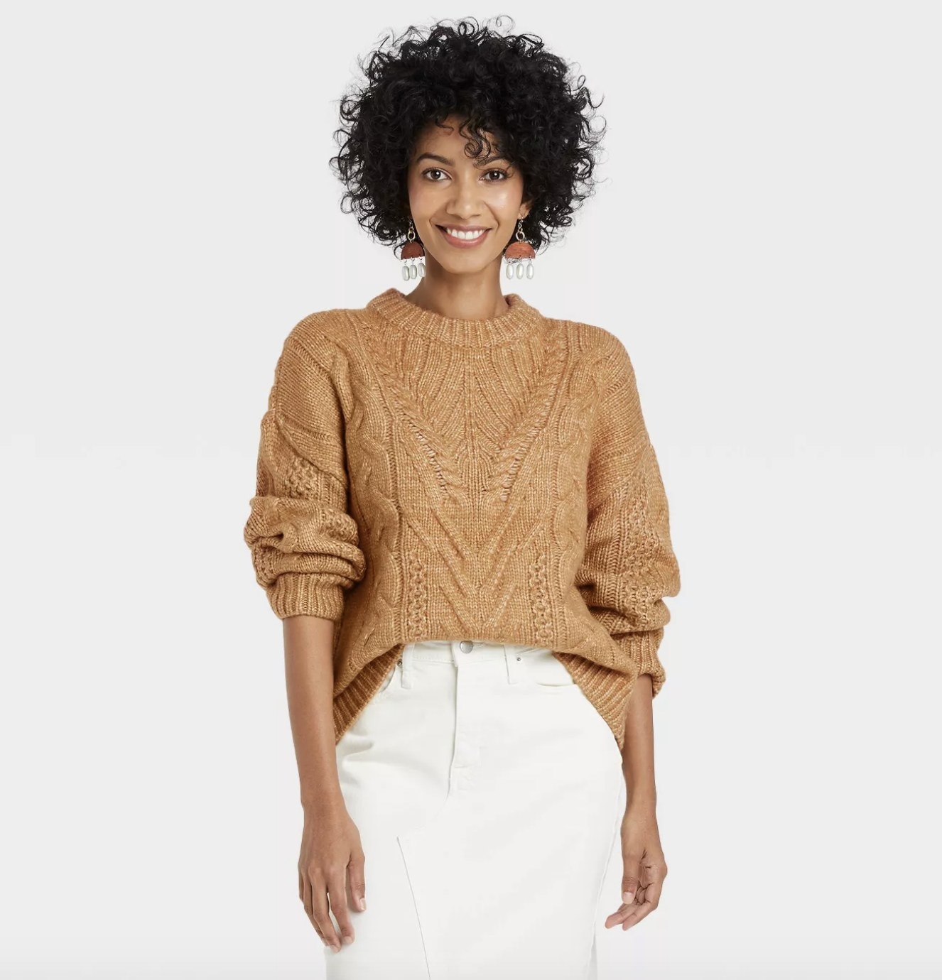 An adult wears the rust-colored sweater with cable knit prints