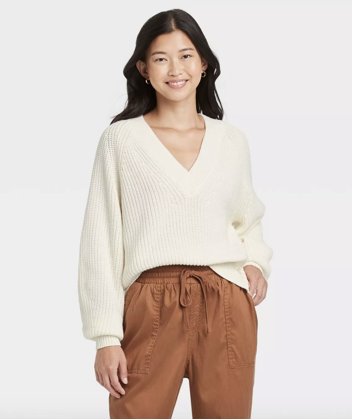 The white chunky v-neck sweater has vertical ribbing and cuffs