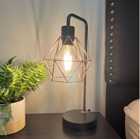 the black and gold table lamp on a side table next to a reviewer&#x27;s bed