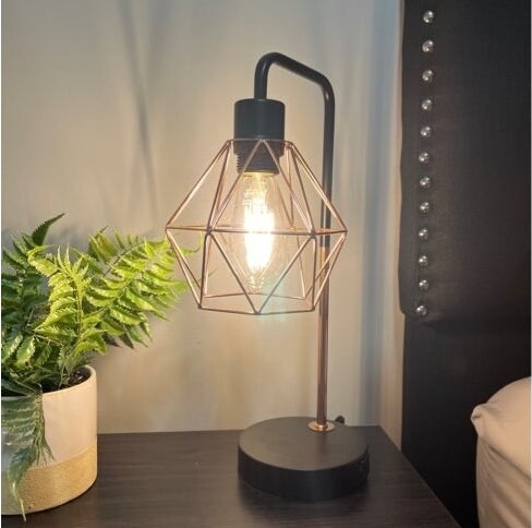 the black and gold table lamp on a side table next to a reviewer&#x27;s bed