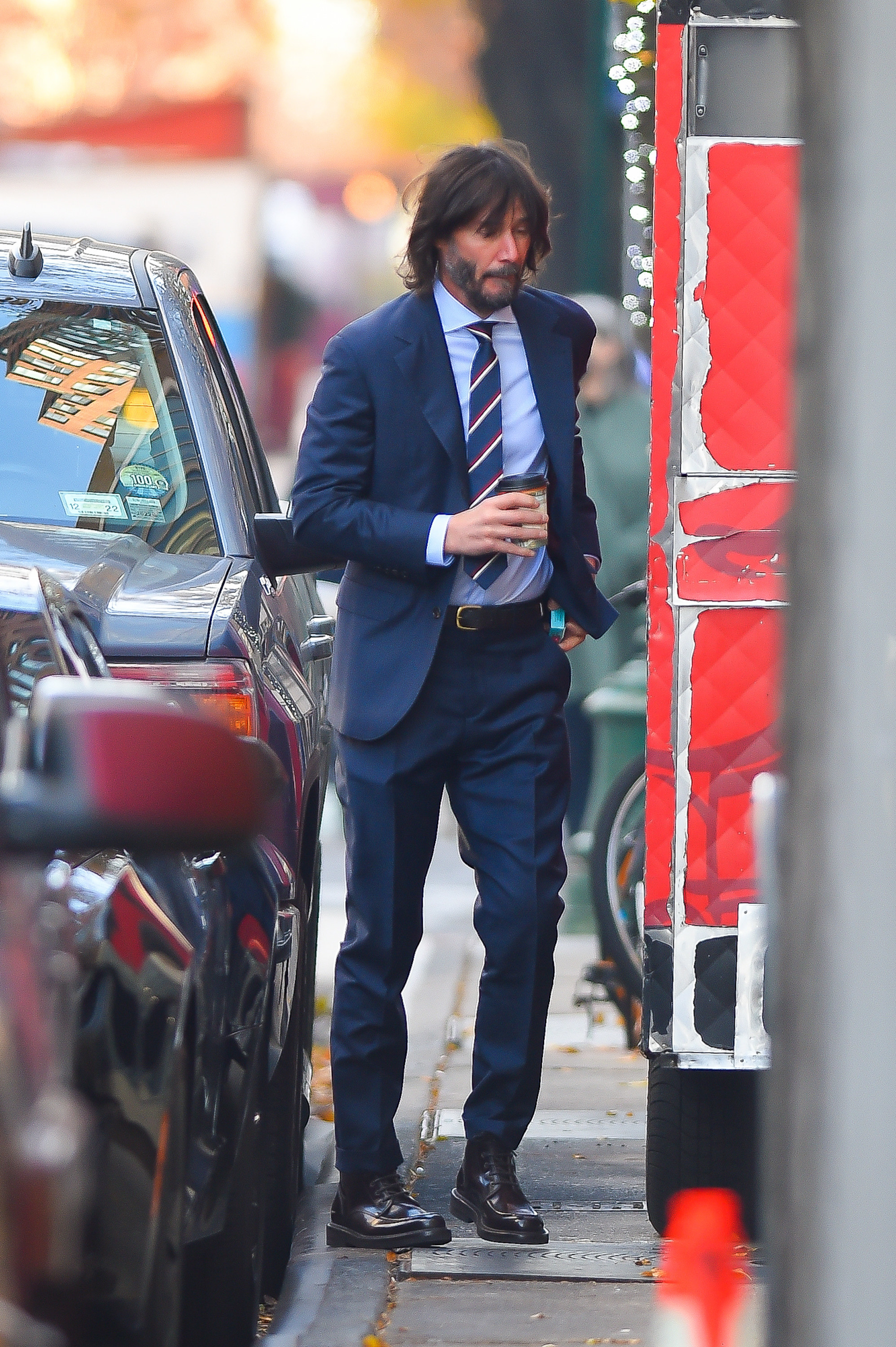 Reeves holds a cup of coffee while standing next to a truck